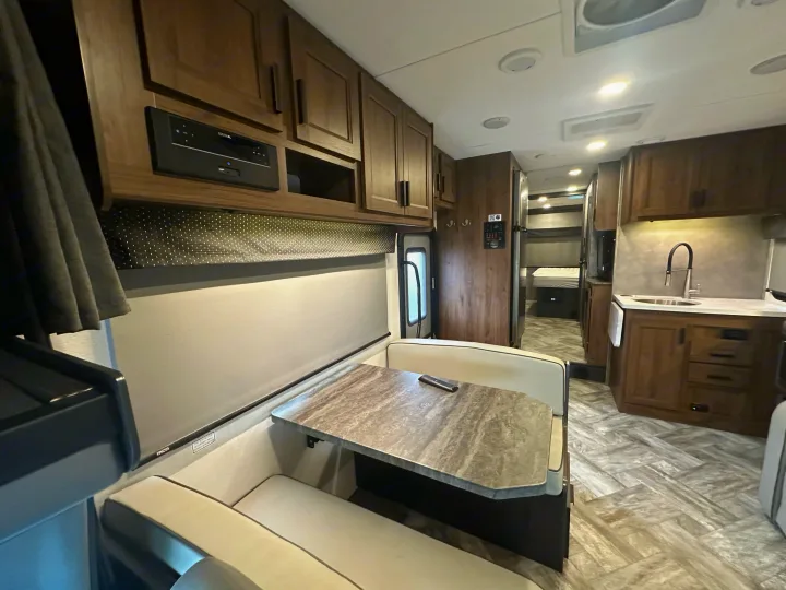 Cozy RV rental interior with a dining booth, modern kitchenette, wood cabinets, and patterned flooring.. Forest River Forester 2022
