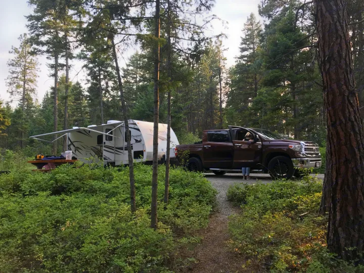 Your next RV rental adventure awaits! A travel trailer & pickup truck set up in a beautiful wooded campsite.. Keystone RV Passport Grand Touring 2014