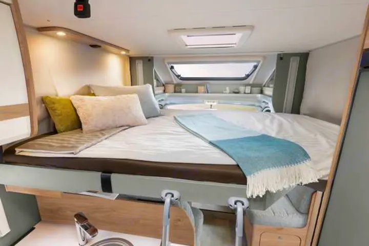 Comfortable RV rental: Spacious bed with skylight, pillows, and compact kitchen below for ideal trips.. Dethleffs Just T7052 DBM 2024