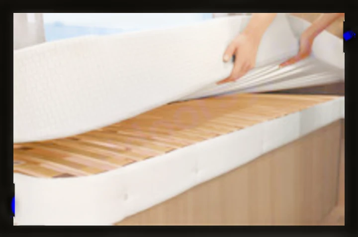 For your RV rental comfort, hands lift a mattress to reveal a sturdy wooden slatted bed base.. Dethleffs Just T7052 DBM 2024