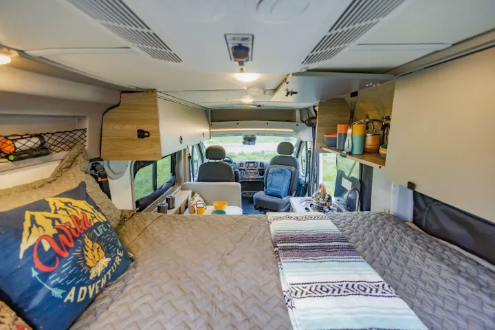 An RV rental's clever interior. From the comfy bed, see the compact kitchen, storage, and front cabin ready for travel.. Winnebago Solis Pocket 2022