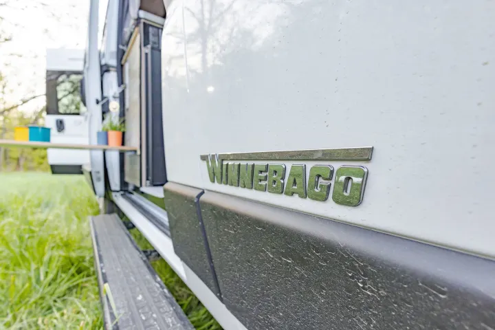 Close-up of a Winnebago RV rental's side panel and logo. This white camper van is ready for an outdoor adventure.. Winnebago Solis Pocket 2022