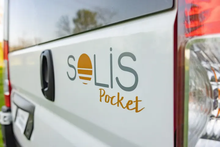 Close-up of a white Solis Pocket RV rental, showcasing its brand logo and rear taillight details on the side of the camper van.. Winnebago Solis Pocket 2022