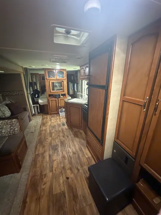 Explore this RV rental's spacious interior: full kitchen, comfy living space, and warm wood flooring.. Keystone RV Passport Grand Touring 2014