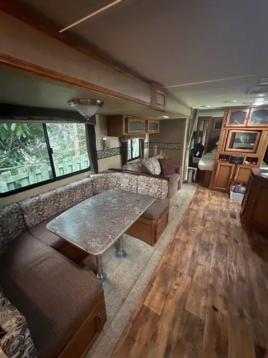 RV rental interior: dining booth with carpet, wood-look floor, kitchen, and bedroom access.. Keystone RV Passport Grand Touring 2014