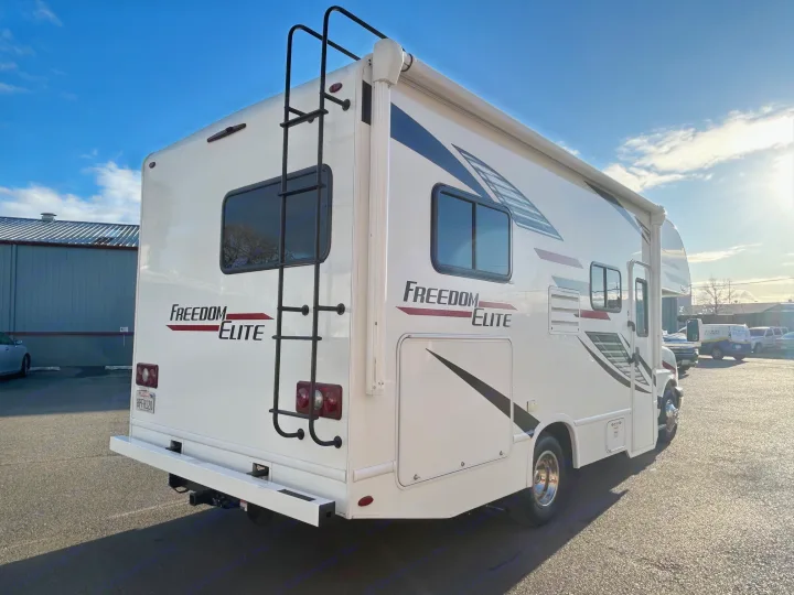 Bright white Freedom Elite rv rental, showcasing its rear ladder & side awning under a clear sky.. Thor Freedom Elite 22HE 2020