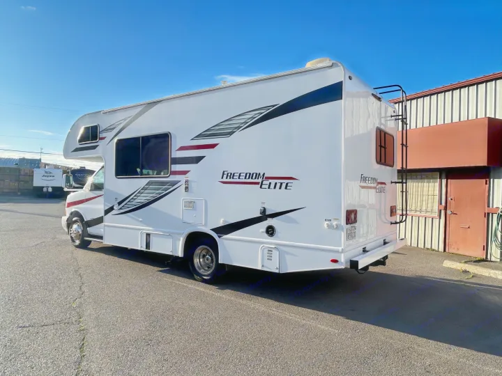 White Freedom Elite Class C RV rental, featuring a rear ladder, parked on asphalt. Ready for your next motorhome adventure.. Thor Freedom Elite 22HE 2020