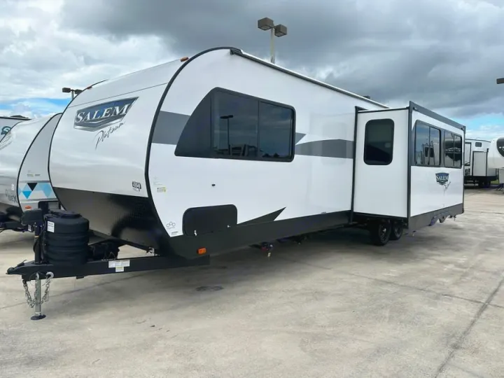 New white travel trailer RV for rv rental, parked on concrete under a cloudy sky. Side slide-out extended.. Forest River Salem Platinum 2024