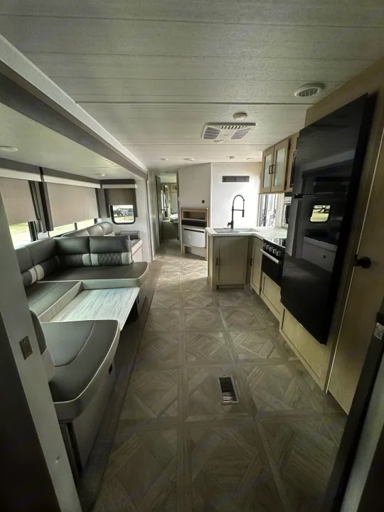 Spacious RV rental interior featuring a modern kitchen, U-shaped dinette, and patterned floor. Ideal for travel.. Forest River Salem Platinum 2024