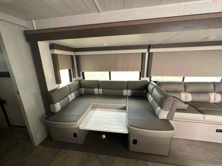 Spacious modern RV rental interior featuring a comfortable U-shaped dinette with gray seating and a central table, ideal for dining.. Forest River Salem Platinum 2024