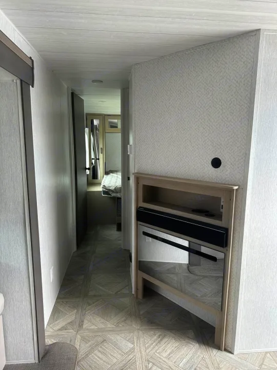Modern RV rental interior with patterned floor, leading to a compact bedroom. Features a built-in entertainment unit.. Forest River Salem Platinum 2024