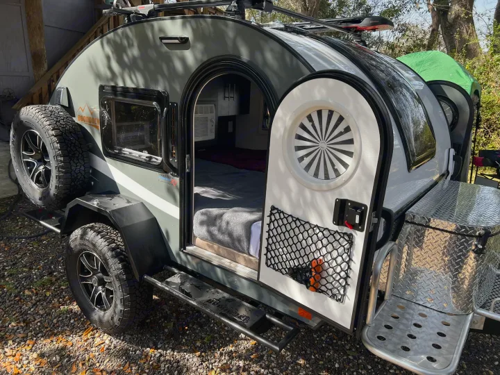 This compact Boondock teardrop trailer, ideal for rv rental, shows its cozy bed, AC, and outdoor adventure gear.. nuCamp T@G 2023