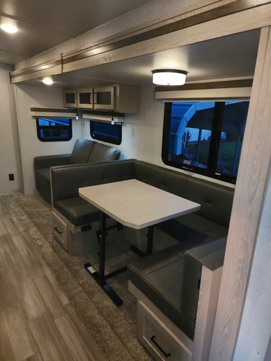 Modern RV rental interior featuring a spacious U-shaped dinette and comfortable sofa in a well-lit living space.. Forest River Rockwood Ultra Lite 2022