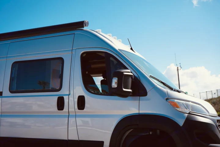 Modern white camper van, perfect for your next RV rental adventure. Equipped with an awning, under a clear blue sky.. Noovo Lite 2023