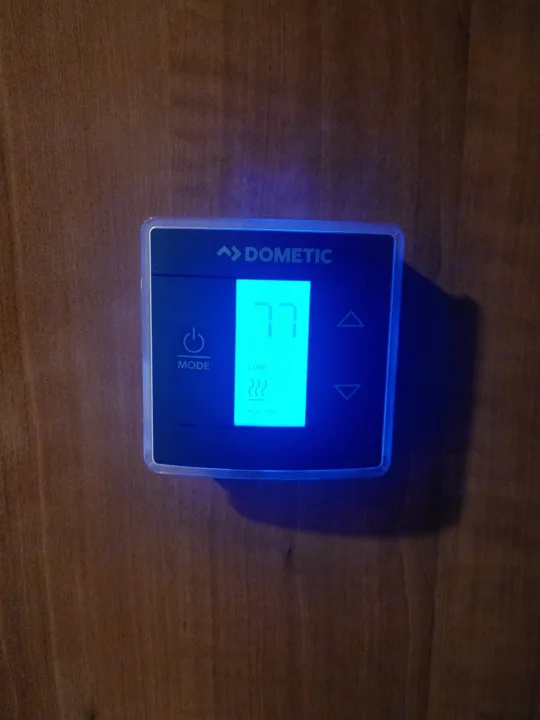 Dometic RV thermostat displaying 77 degrees (Heat Pump, Low fan) on wood. Essential for comfortable RV rental stays.. Other Other 2019