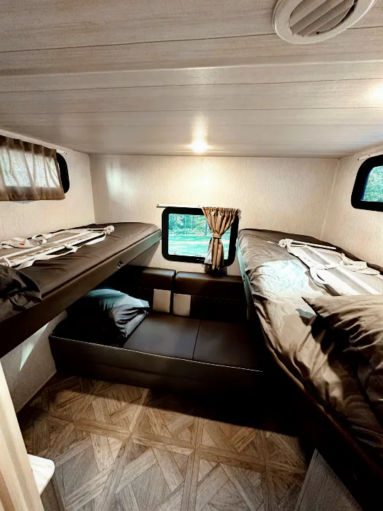 Cozy RV rental interior with practical bunk beds and a central seating area, perfect for a family trip.. Forest River Wildwood X-Lite Platinum 2024