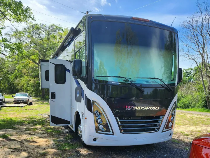 Spacious white and black WindSport motorhome parked outdoors. Driver's door open, awning extended. Perfect for an RV rental.. Thor Windsport 2023