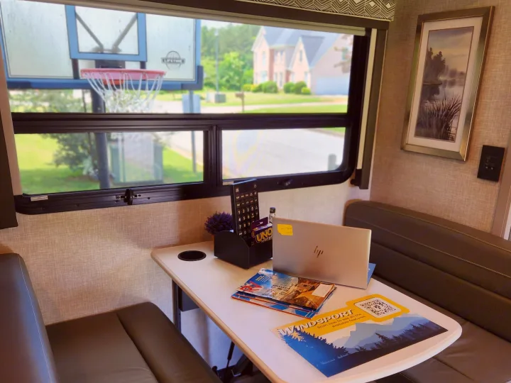 This RV rental's WindSport model features a cozy dinette, perfect for work or play with games and a laptop, offering a home-like mobile workspace.. Thor Windsport 2023