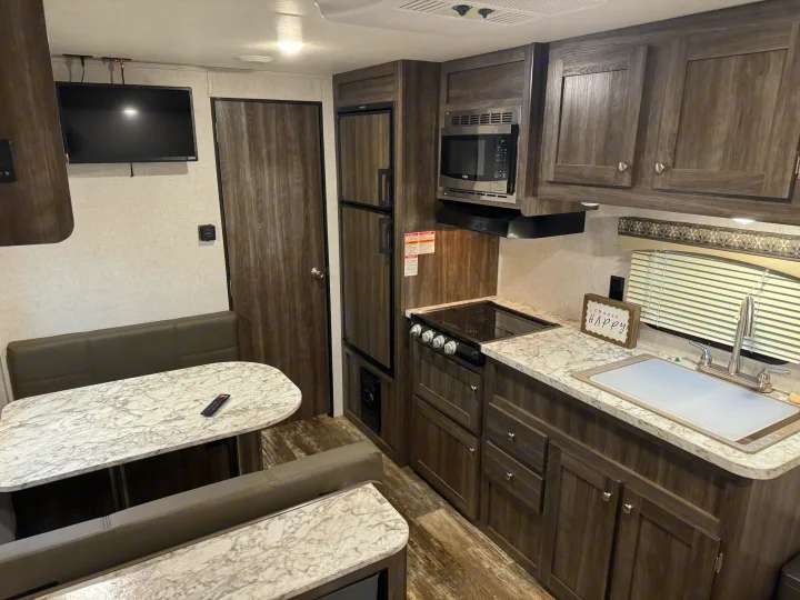 Modern RV rental's kitchen, dinette, and living space, featuring wood and marble finishes for comfortable travel.. Starcraft Autumn Ridge Outfitter 2020