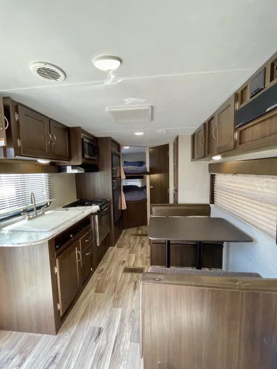 Modern rv rental interior with a fully-equipped kitchen, dining booth, and rear bunk beds, perfect for family trips.. Keystone RV Springdale Eco-Lite 2018