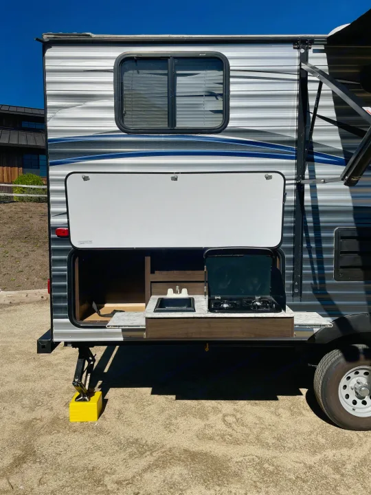 This RV rental showcases a practical outdoor kitchen with a sink and stovetop, ready for camping adventures.. Keystone RV Springdale Eco-Lite 2018
