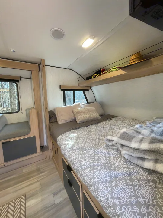 Inside a comfortable RV rental: bed with storage, compact dinette, and overhead shelf. Ideal for road trips.. Cruiser RV Hitch 2022