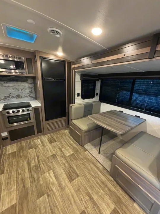 Compact RV rental interior featuring a modern kitchen with appliances & a comfy dinette. Ideal for adventures!. Crossroads RV Sunset Trail Super Lite 2023
