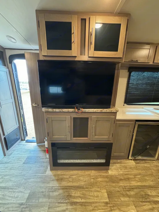 RV rental interior: A well-appointed living area with a TV, electric fireplace, cabinets, and compact kitchen.. Crossroads RV Sunset Trail Super Lite 2023