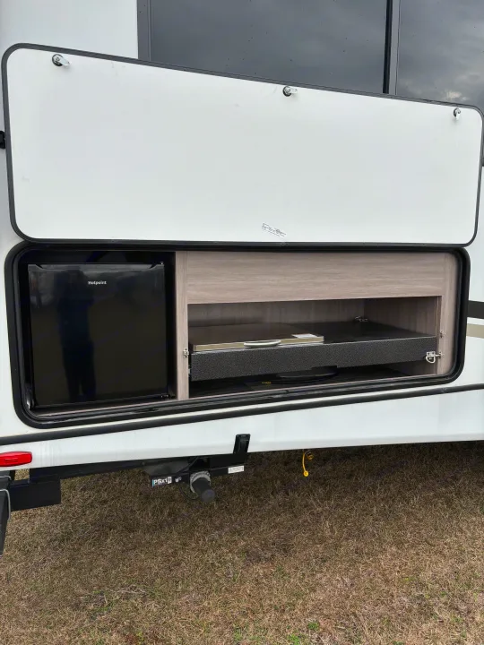 Outdoor kitchen of an RV rental: Hotpoint mini-fridge & pull-out counter for cooking or prep.. Crossroads RV Sunset Trail Super Lite 2023