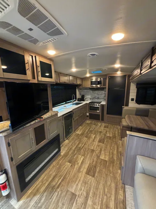 Spacious RV rental interior featuring a modern kitchen, dining area, TV, and fireplace.. Crossroads RV Sunset Trail Super Lite 2023