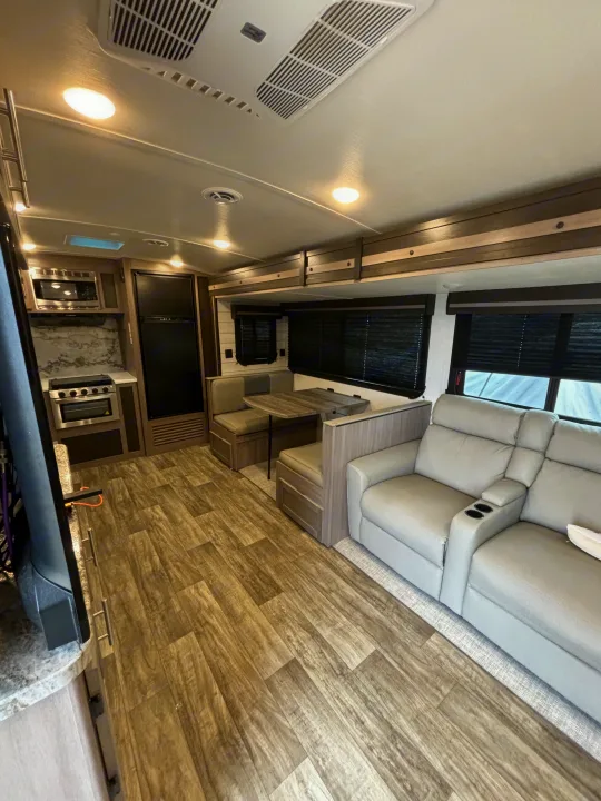 Modern RV rental interior: Full kitchen, cozy dinette, and reclining sofa with cup holders.. Crossroads RV Sunset Trail Super Lite 2023