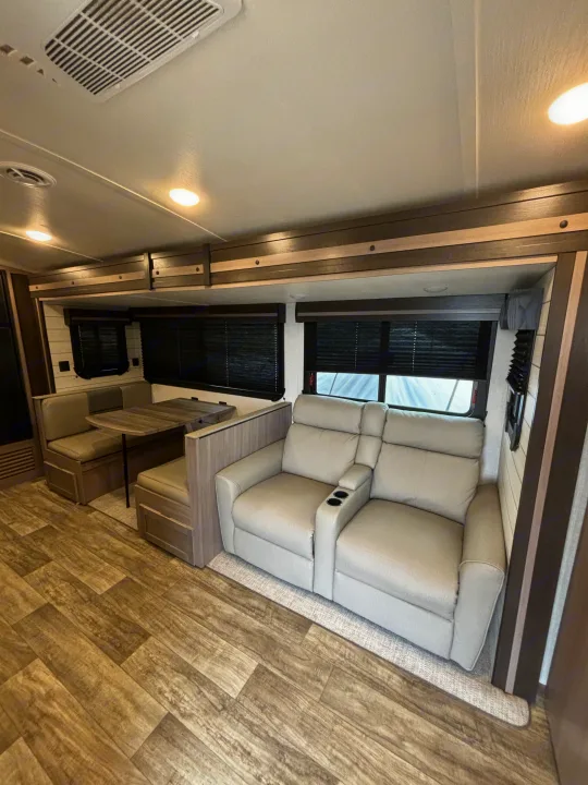 Spacious RV rental interior featuring a cozy dinette, comfortable theater recliners with cup holders, and stylish wood-look flooring.. Crossroads RV Sunset Trail Super Lite 2023