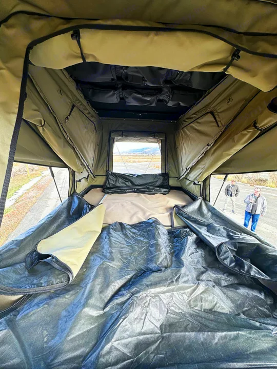 Inside a large rooftop tent, highlighting its mattress, storage, and scenic outdoor view. Ideal for RV rental road trips.. Other Other 2024
