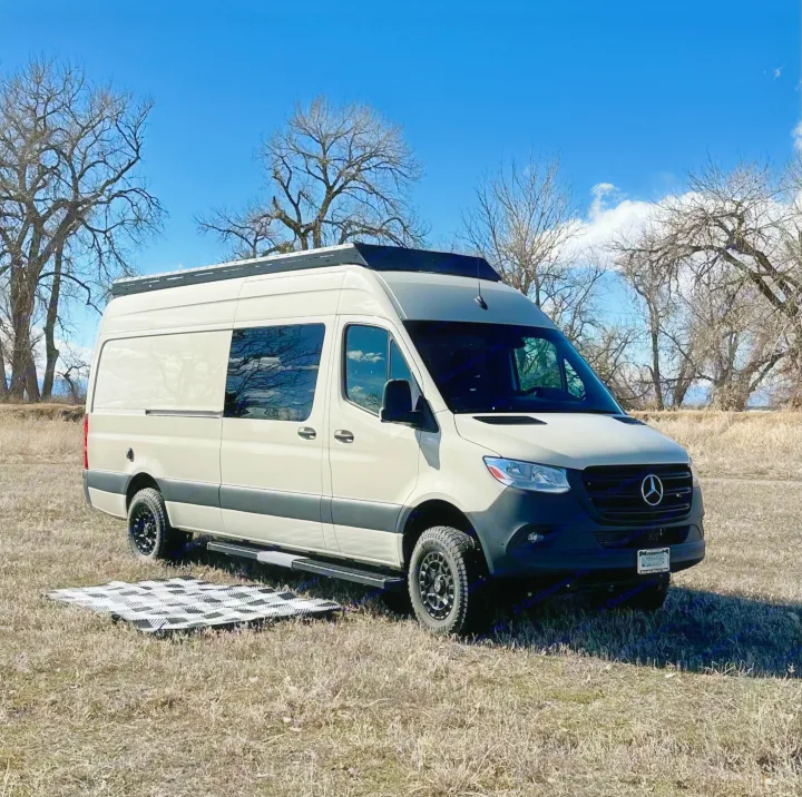 Light Mercedes Sprinter RV rental camper van on dry grass, trees under blue sky. Perfect for your next road trip.. Mercedes-Benz Sprinter High Roof Medium wheelbase 2021