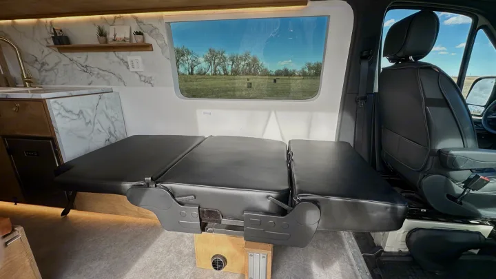This RV rental interior features a versatile convertible bench/bed, full kitchenette, and front seats, perfect for mobile living.. Mercedes-Benz Sprinter High Roof Medium wheelbase 2021