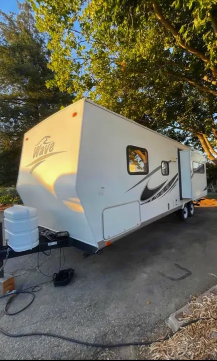 Spacious white "Wave" travel trailer RV, parked under trees. Great for your next RV rental adventure!. Thor Motor Coach Wave 2007