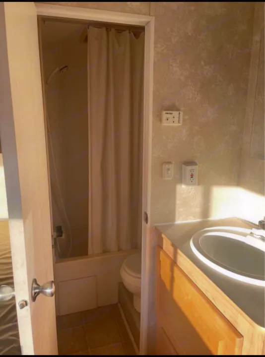 Functional RV rental bathroom with a shower/tub, toilet, and vanity sink. Bright with natural light.. Thor Motor Coach Wave 2007