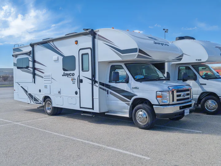 White Jayco Redhawk Class C motorhome, perfect for an RV rental trip, parked alongside another RV under a blue sky.. Jayco Redhawk 2019