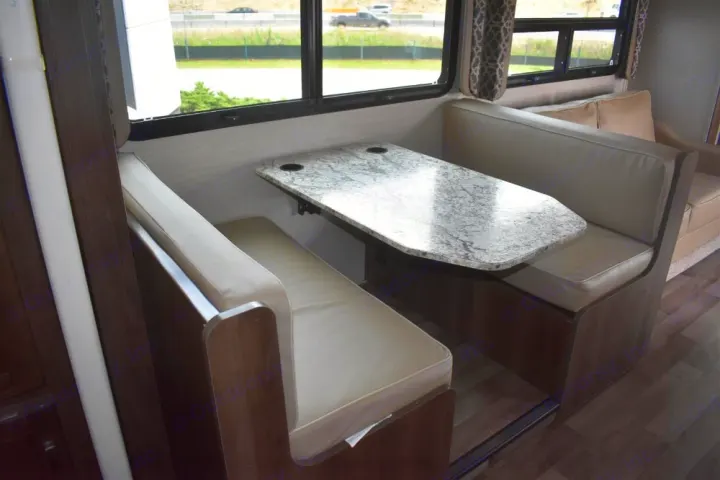 RV rental interior: A functional dinette with a light-colored table and cushioned booth seating for your camper.. Jayco Redhawk 2019
