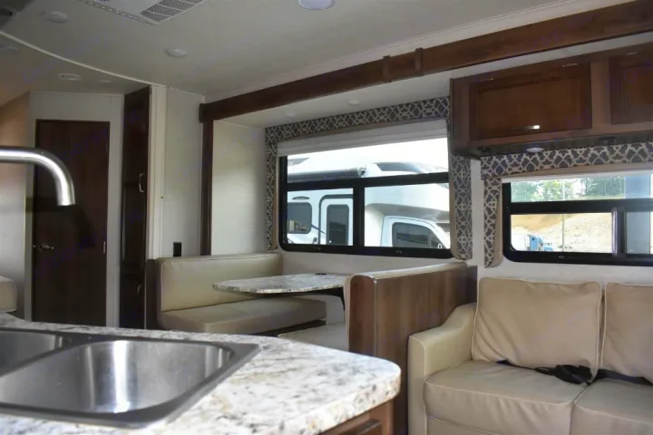 Comfortable RV rental living area features a dinette, plush sofa, and a well-equipped kitchen with sink. Perfect for trips.. Jayco Redhawk 2019