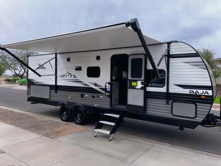 White and grey Jay Flight Baja travel trailer with awning & steps out. Perfect RV rental for your next outdoor adventure.. Jayco Jay Flight Baja Edition 2023