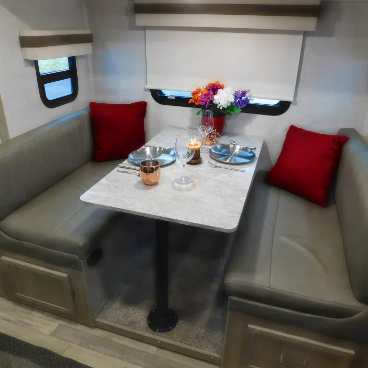 Cozy RV rental dinette interior featuring a set table with decor, flanked by comfy upholstered benches.. Forest River GeoPro 20BHS 2022