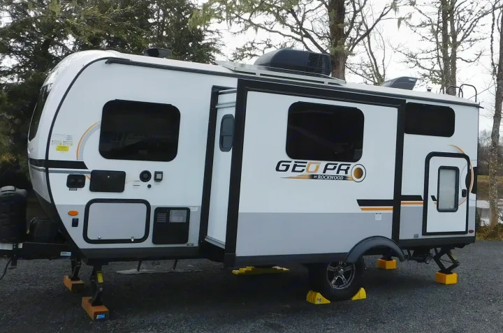 This white and gray GEO PRO travel trailer RV rental is fully leveled at a gravel campsite, ready for adventure.. Forest River GeoPro 20BHS 2022