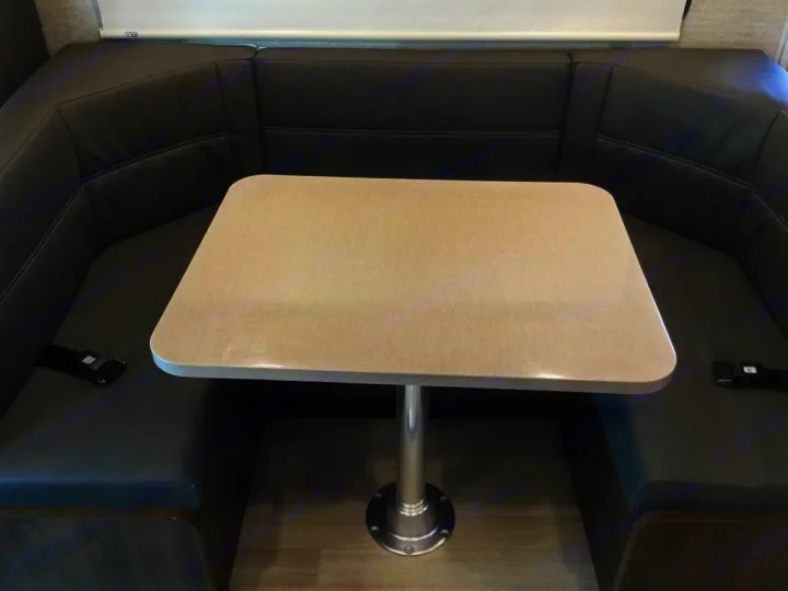 RV rental dinette: U-shaped dark seating with a light table on a pedestal, and visible seatbelts for travel.. Winnebago Minnie Winnie 2024