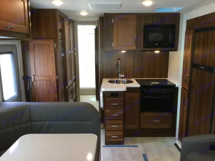 Spacious RV rental interior featuring a modern kitchen with microwave, sink, stovetop/oven, and cozy dining seating.. Winnebago Minnie Winnie 2024