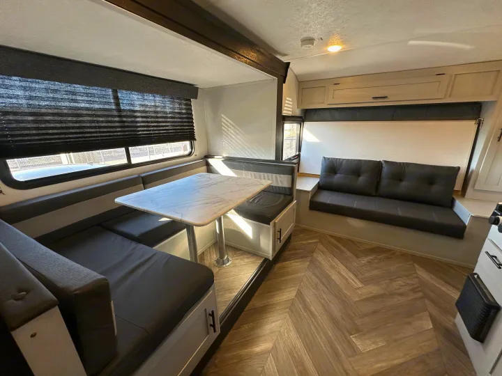 This RV rental features a cozy interior with a U-shaped dinette, comfortable dark sofa, and herringbone wood-look floor.. Forest River Salem FSX 2022
