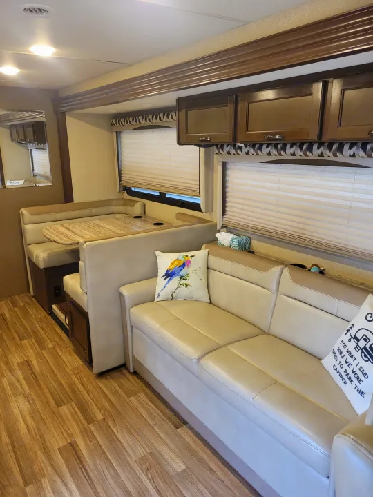 RV rental interior showing comfortable living space with dinette, sofa, and wood-look flooring.. Thor A.C.E. 2018