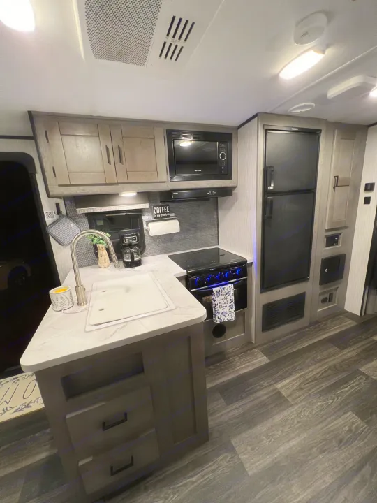 Well-equipped RV rental kitchen interior with sink, microwave, stove, and refrigerator for comfortable travels.. Heartland RVs Mallard 2022