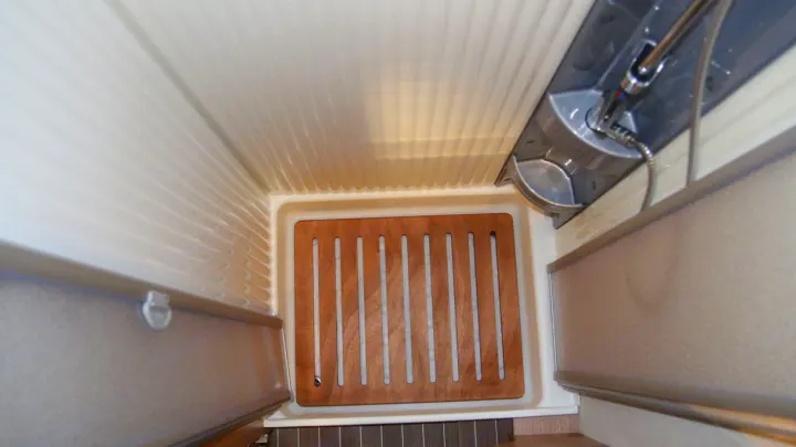 Overhead view of an RV rental shower, with slatted wood floor, showerhead, and collapsible walls for compact design.. Sunlight A68 2024