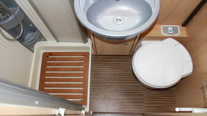 View of a compact RV rental bathroom featuring a shower, small sink, and toilet, optimizing space.. Sunlight A68 2024
